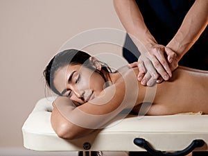 A young woman gets a massage procedure. Masseur makes back massage.