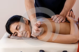 A young woman gets a massage procedure. Masseur makes back massage.