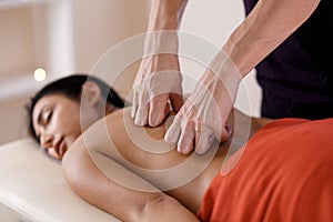 A young woman gets a massage procedure. Masseur makes back massage.
