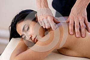 A young woman gets a massage procedure. Masseur makes back massage.