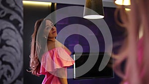 Young woman gets ready in front of a mirror, looking at herself happy