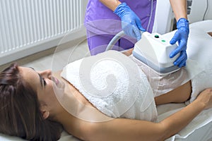 Young woman getting cryolipolyse treatment in cosmetic cabinet