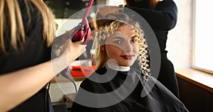 Young Woman Getting Curly Hair by Curling Iron