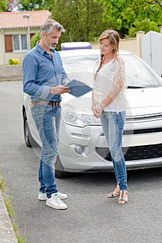 Young woman getting driving lesson near car