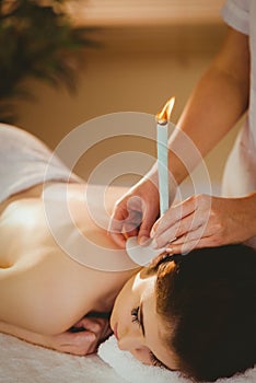 Young woman getting ear candling treatment