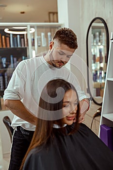 Young woman getting a haircut by professional male hairdresser at beauty salon