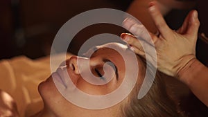 Young woman getting head massage in beauty spa salon. Close up portrait woman receiving head skin massage in cosmetic