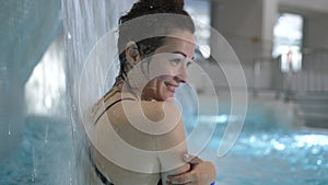Young woman getting hydrotherapy in pool. Beautiful girl having spa treatment at wellness center. Pretty girl relaxing