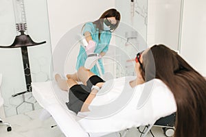 Young woman getting laser treatment on leg at spa. Laser epilation and cosmetology