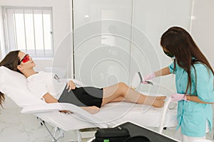 Young woman getting laser treatment on leg at spa. Laser epilation and cosmetology