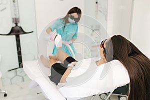 Young woman getting laser treatment on leg at spa. Laser epilation and cosmetology