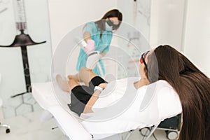 Young woman getting laser treatment on leg at spa. Laser epilation and cosmetology