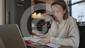 Young woman getting stressed over finances. Young woman looking worried over bills in kitchen. Working from home in