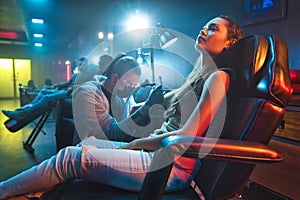 Young Woman Getting Tattoos In Beauty Parlor With Tattooist Working