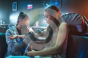 Young Woman Getting Tattoos In Beauty Parlor With Tattooist Working