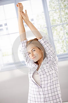 Young woman getting up stretching in the morning
