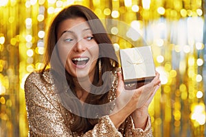 Young woman with gift over gold background