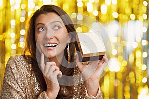 Young woman with gift over gold background