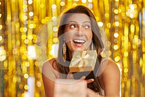 Young woman with gift over gold background