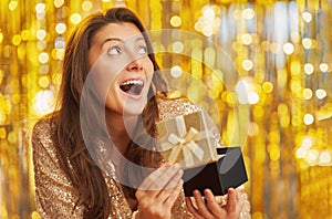 Young woman with gift over gold background