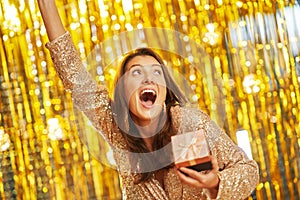 Young woman with gift over gold background