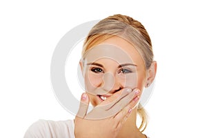 Young woman giggles covering her mouth with hand