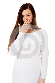 Young woman giggles covering her mouth with hand