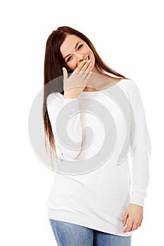 Young woman giggles covering her mouth with hand