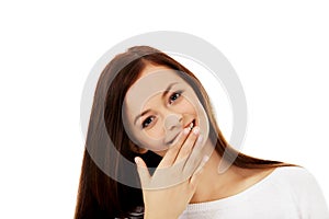 Young woman giggles covering her mouth with hand