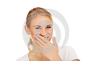 Young woman giggles covering her mouth with hand