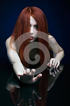 Young woman with ginger hair over reflection mirror on blue back