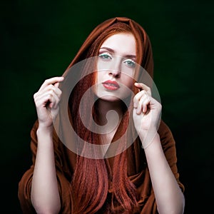 Young woman with ginger hair and scarf on green background