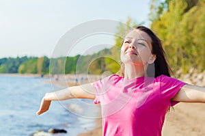 Young woman, girl on the beach enjoys and breathes clean air