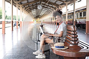 Young woman girl female sitting use computer laptop and travel bag suit case on the floor at station