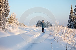 Young woman girl jumping, rejoices on a forest road on a frosty sunny afternoon