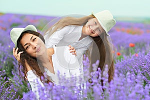 Young woman and girl are in the lavender field, beautiful summer landscape with red poppy flowers