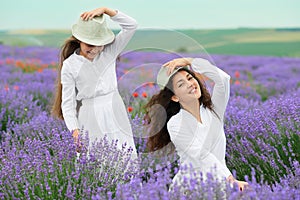 Young woman and girl are in the lavender field, beautiful summer landscape with red poppy flowers