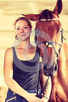 Young woman girl in stable with horse.