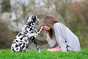 Young woman gives her Dalmatian dog a kiss on the paw