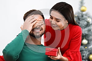 Young woman giving Christmas gift to her boyfriend