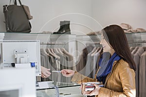 Young woman giving credit card to cashier
