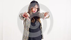 young woman giving dislike and disagree gesture in a stylish outfit against a white background posing