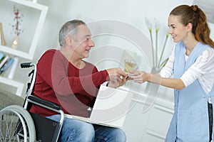 Young woman giving glass water to disabled man