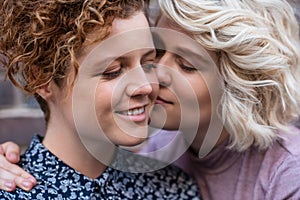 Young woman giving her smiling girlfriend an affectionate kiss