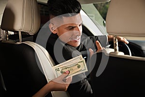 Young woman giving money taxi driver in modern car, closeup
