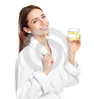 Young woman with glass of lemon water on background