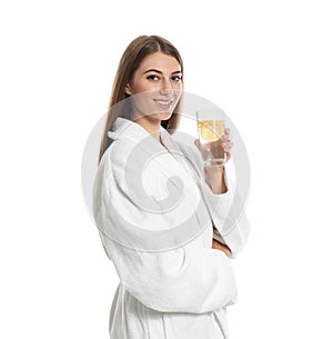 Young woman with glass of lemon water on background