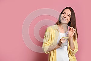 Young woman with glass of lemon water on background. Space for text