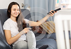 Woman with glass of red wine watching tv at home