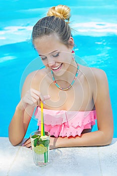 Young woman with a glass of refreshing lemonade in the pool